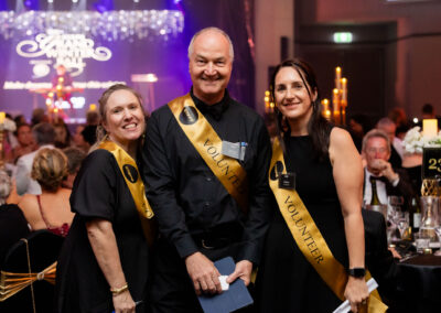 Volunteers smiling while helping with the STEPS Grand Winter Ball.